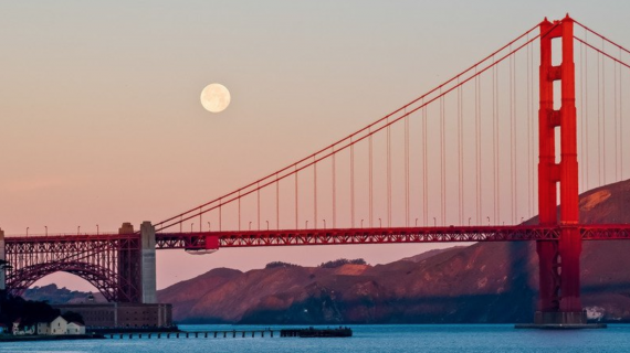 The Golden Gate Bridge at dusk with the Moon in the background.